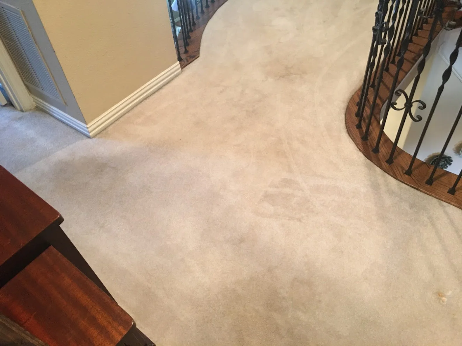Beige carpeted hallway with staircase railing and cream colored walls